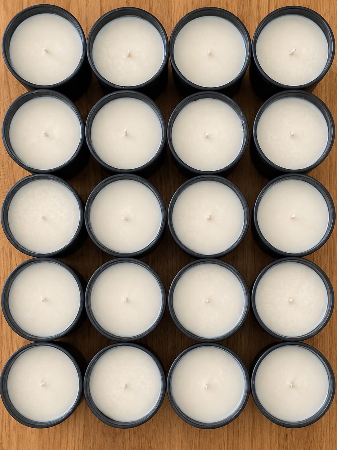The same jars, now cooled and set, wicks trimmed back, on the wooden table.