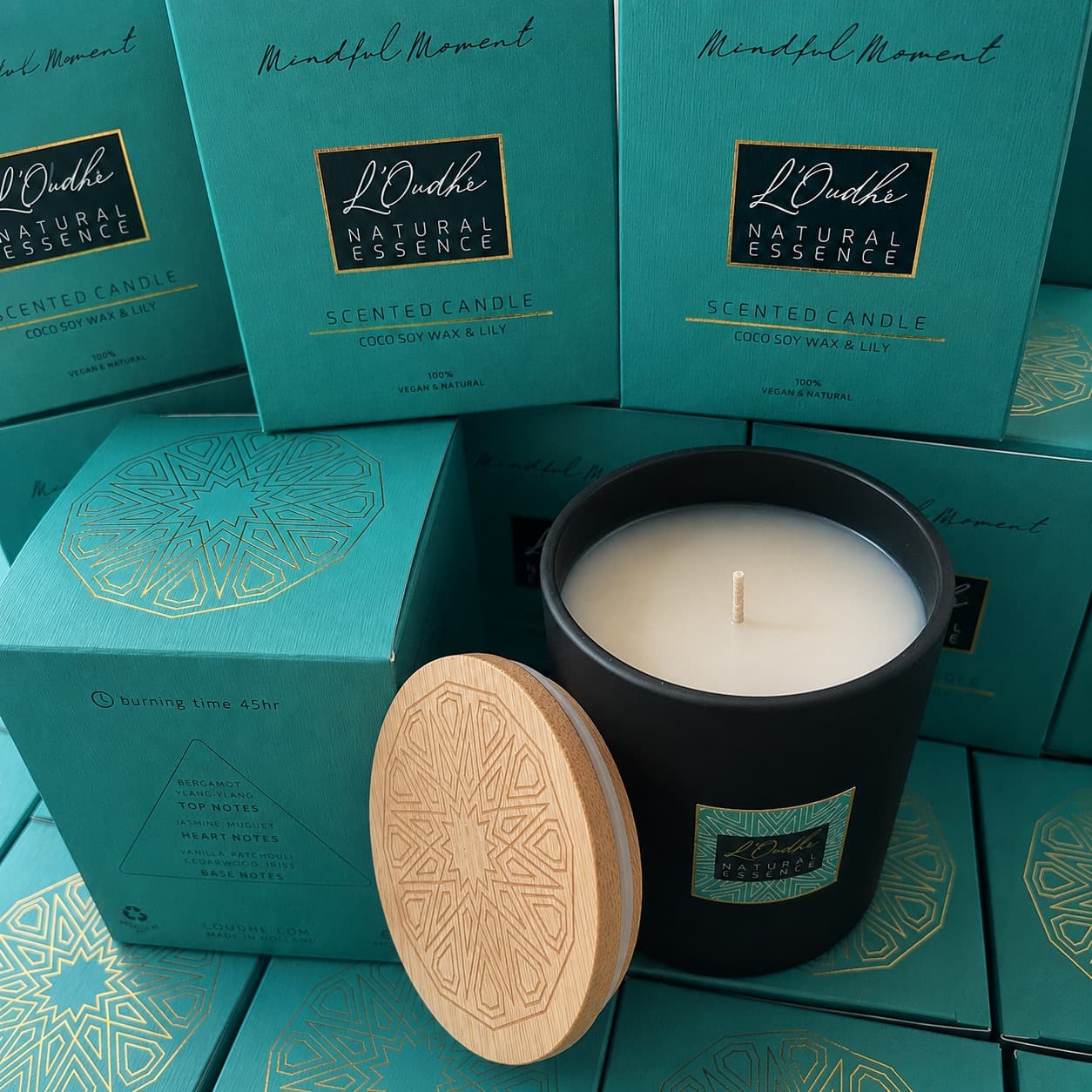Mindful Moment open beside its stacked teal boxes printed with the gold zellige medallion, the wooden lid with its milled star leaning against the jar.